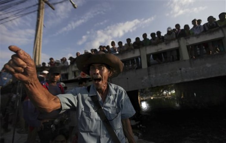 Manit Gongpeng, 52, an agitated Thai flood victim, yells at policemen, unseen, as he and other residents try to force authorities to let some floodwater flow out from their area on the outskirts of Bangkok, Thailand, Monday, Oct. 31, 2011. Higher than normal tides pushing up the Chao Phraya River from the Gulf of Thailand in recent days have complicated efforts to drain the floodwater that has been surging through the city as it makes its way from provinces that have been submerged and suffering for up to two months. (AP Photo/Altaf Qadri)